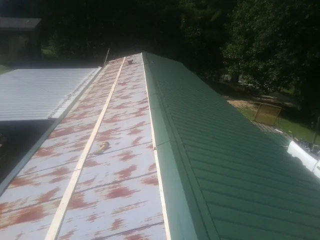 Old rusted panels beside newly installed green metal roofing — Wind Damage Roof Repair by Roofing Brothers in Allen Park