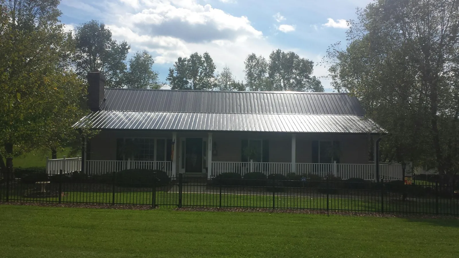 Gray metal roof on a brick ranch with a full width front porch — Gutter Guard Installation work by our crew in Allen Park