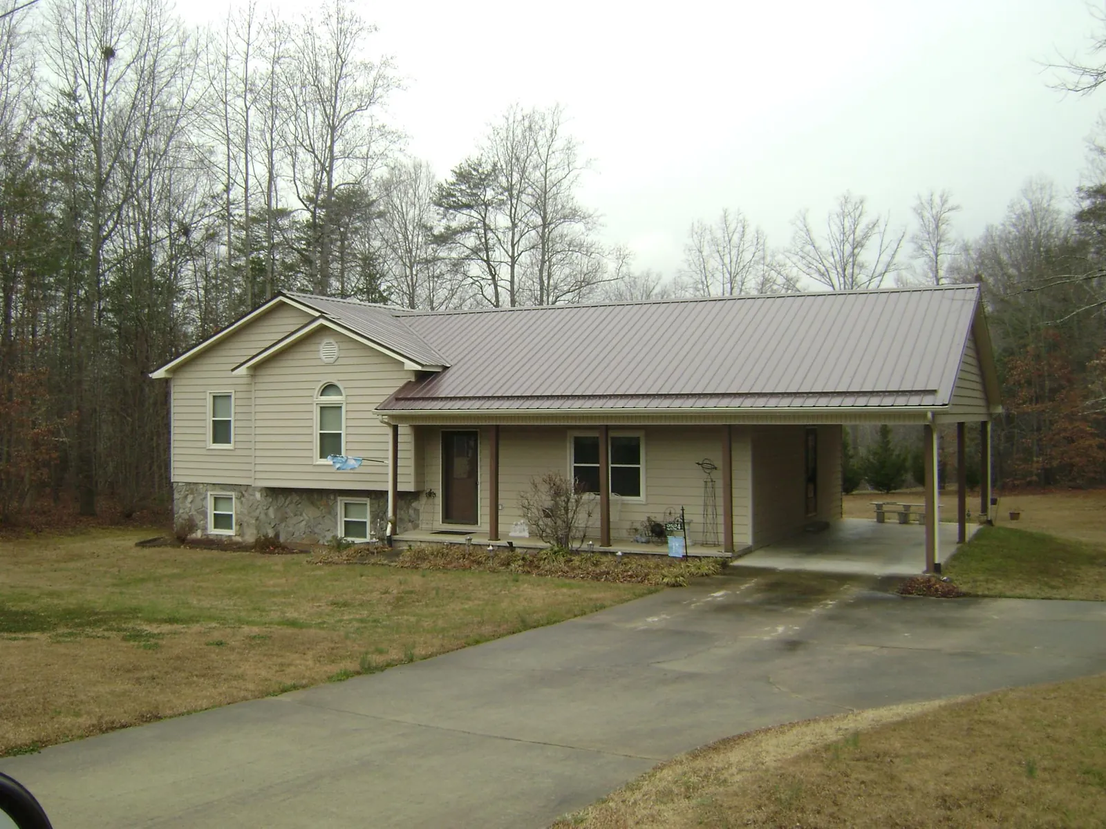 Brown metal roof on a tan split level home with an attached carport in Allen Park