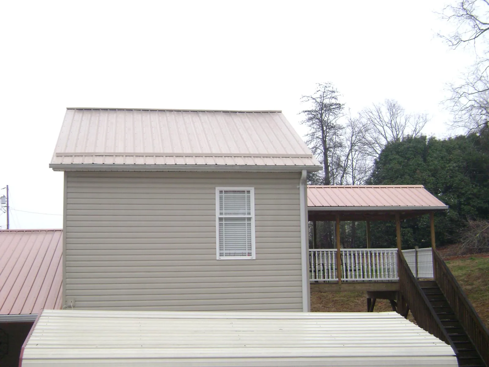 Tan metal roofs on a two story addition and attached porch, from a Roof Replacement job in Allen Park