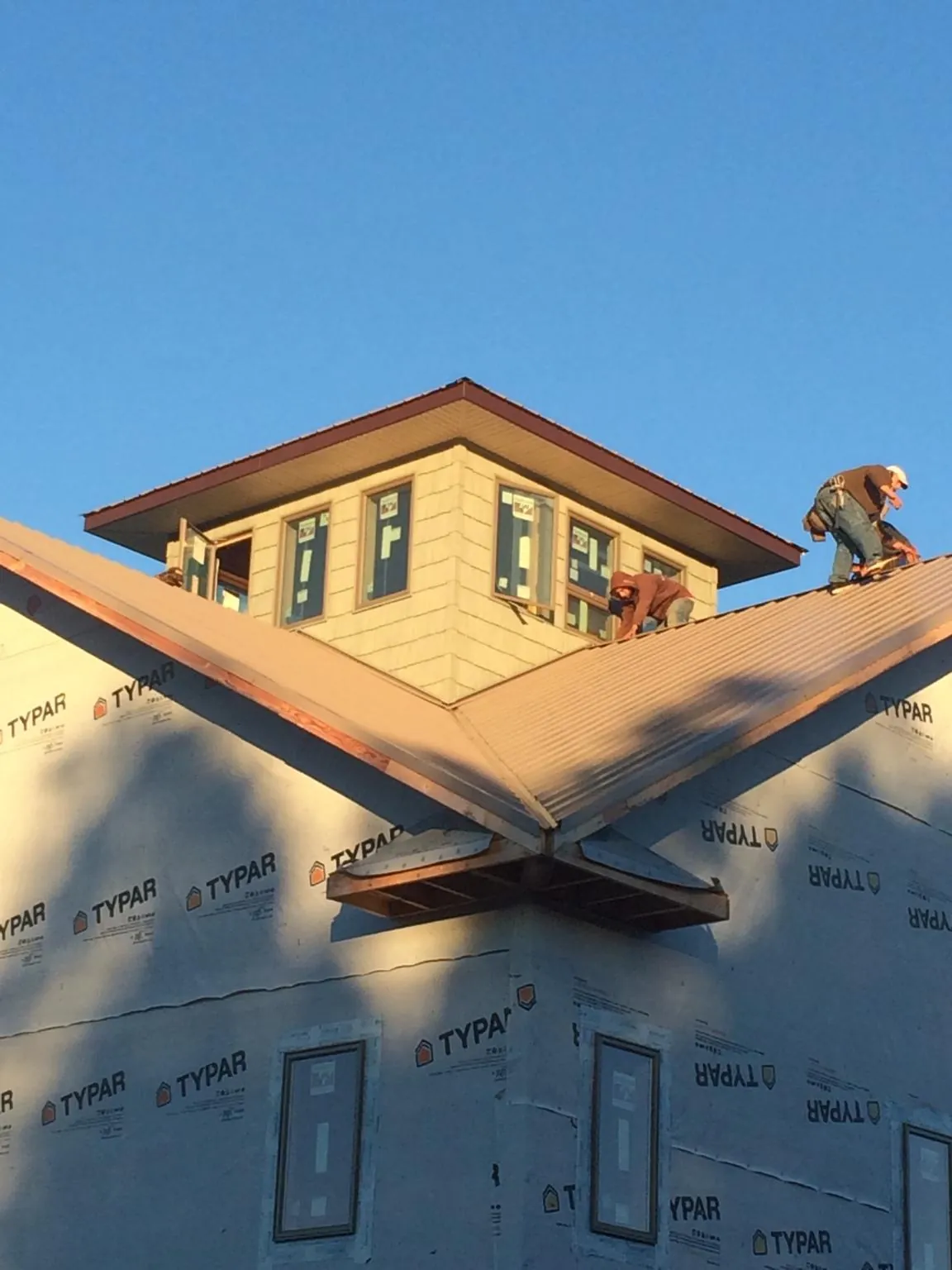 Roofers working around a rooftop cupola on a new metal roof at sunset — Roof Waterproofing in Allen Park by Roofing Brothers